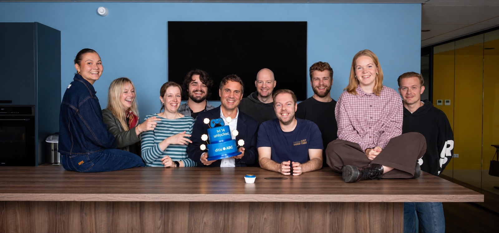 Het team van ditisABC rond een blauwe taart met de tekst lvl 14 unlocked